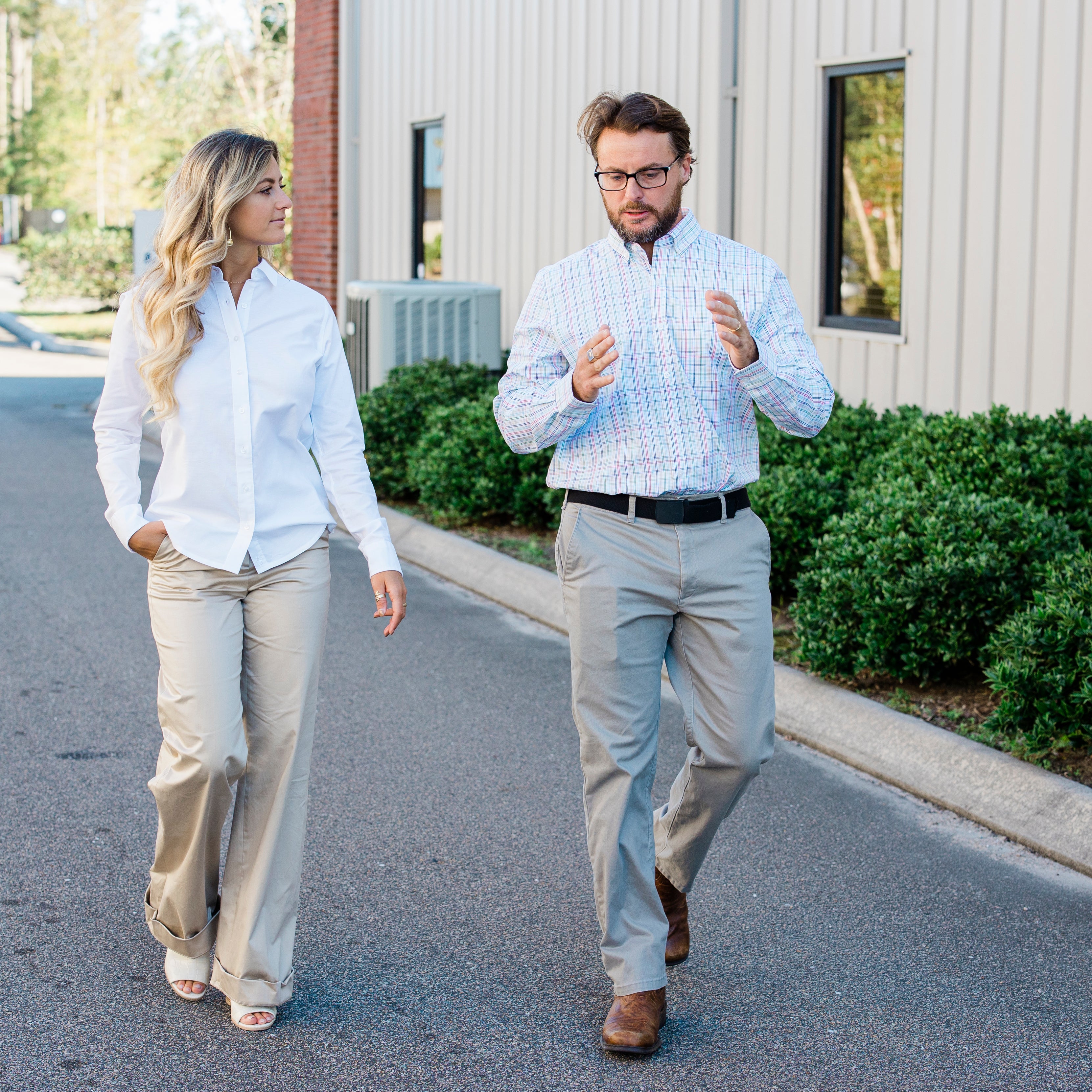 Man and woman walking and speaking outside of Port City Apparel.